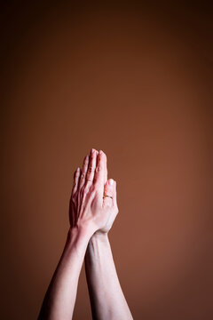 Hand in a praying gesture on brown background