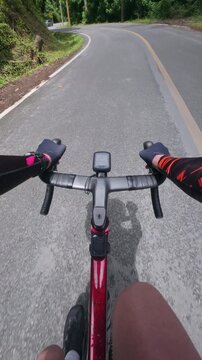 First-person point of view of a road cyclist riding uphill on a quiet mountain road surrounded by lush tropical forest. The immersive cycling footage captures endurance training, outdoor adventure, fi