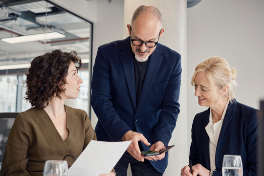 Businessman shows smartphone to colleague in modern London office