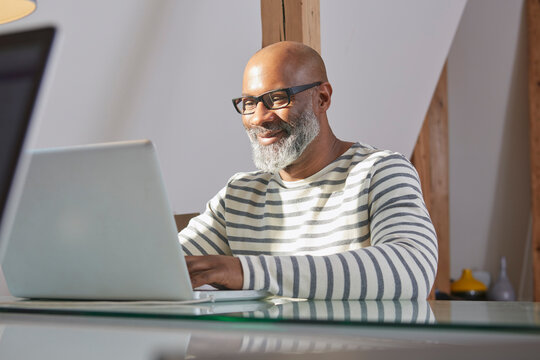 Portrait of smiling man sitting at his desk working with laptop