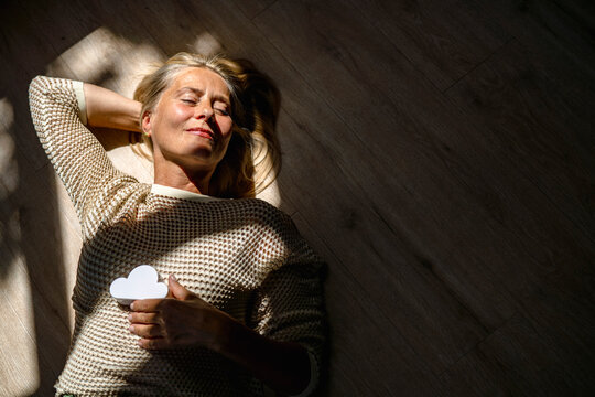 Smiling woman relaxing on floor with cloud model at home