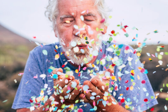 Senior man blowing confetti outdoors