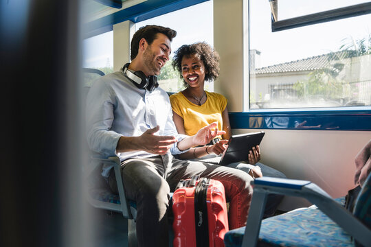 Happy young couple using tablet in a train
