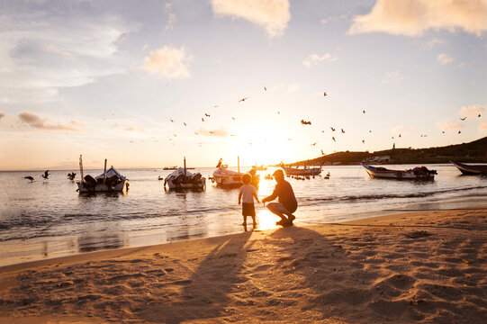 Venezuela, Isla Margarita, Juan Griego, little boy and his grandfather at seafront by sunset