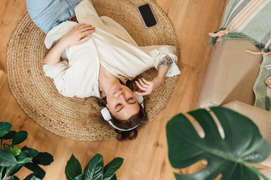 Woman with eyes closed listening music while lying on floor at home