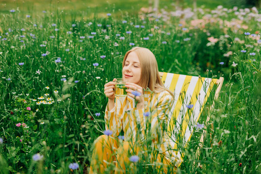 Woman relaxes in a wildflower garden drinking chamomile tea