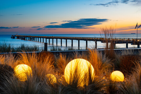 Germany, Mecklenburg-Vorpommern, Binz, Glowing spheres on beach of Rugen island with Seebrucke Binz pier in background