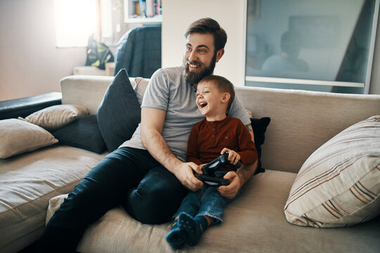 Happy father and son sitting together on the couch playing computer game