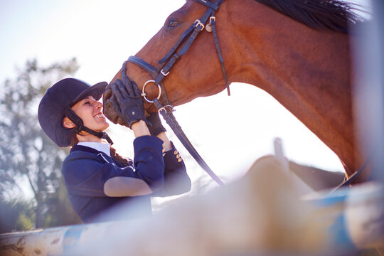 Smiling young woman with horse on show jumping course