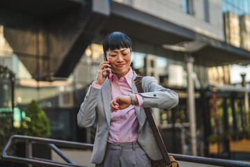 Fototapeta premium Stressed businesswoman talking on phone checking time