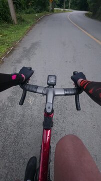 First-person point of view of a road cyclist riding along a quiet winding mountain road surrounded by lush tropical countryside. The immersive footage captures endurance cycling, outdoor fitness, scen