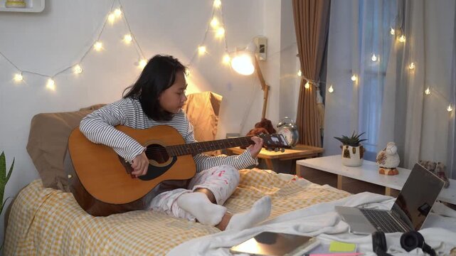 Young Girl carefully practicing chords on an acoustic guitar in Cozy Bedroom at Home	