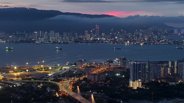 City lights glow against a twilight sky at Perai, Penang. Background is vibrant Penang island