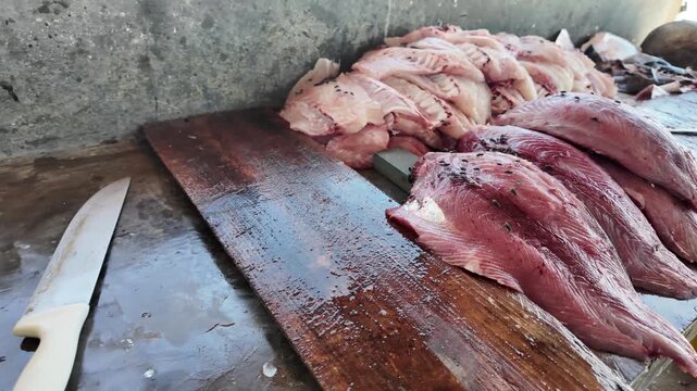 Tracking shot across a wooden surface displaying raw tuna and prepared fillets, showcasing the authentic process of artisanal seafood preparation.