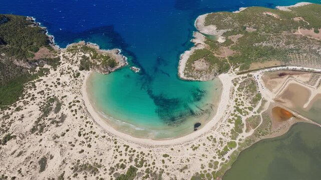 Aerial overview of Voidokilia Beach in Pilos Messinia with turquoise lagoon, drone tilt down