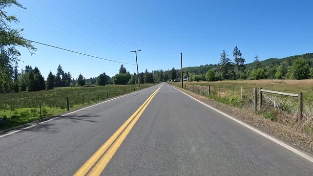 4K smooth action camera driving  footage from a hood mounted driver's POV along a scenic countryside road in Oregon, USA with forest, rural homes, fields and Pacific Northwest scenery