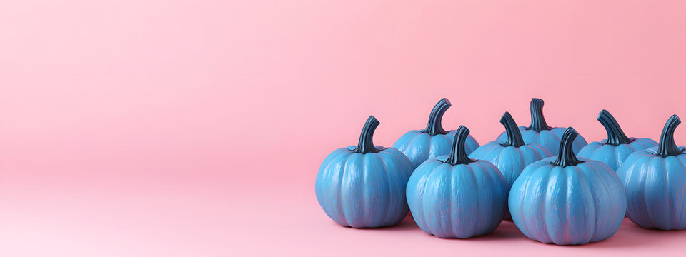 Decorative blue pumpkins placed against a soft pink studio background with ample text space offer a modern autumnal style and seasonal banner concept