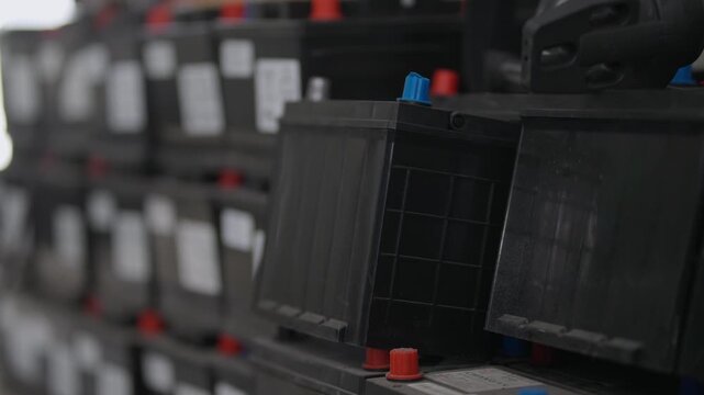 Rows of black batteries sit stacked tightly. Red and blue terminals show clearly on each unit.