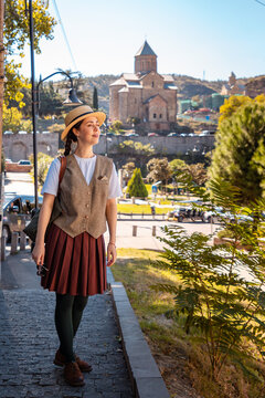 Young traveler in a straw hat looking away near a historic monastery