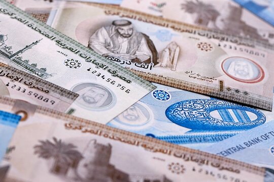 UAE dirham money bills pile on table. United Arab Emirates banknotes of AED currency close up.