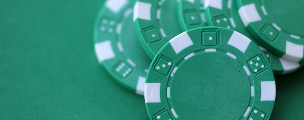 Naklejka premium Green casino poker chips on green gaming table close up. Few amount of green casino chips