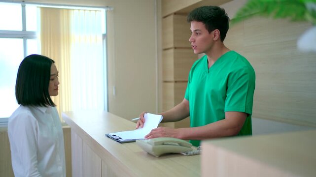 Female patient checking in and filling form at hospital reception.