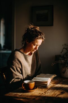 Serene scene of a female reader with an open Bible on a wooden table