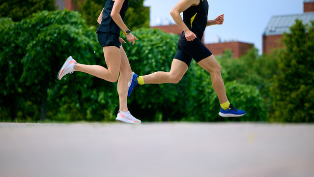 Cropped running legs moving fast through urban park route. Concept of sport footwear advertising, speed training, urban cardio workout, and dynamic runner lifestyle visuals.