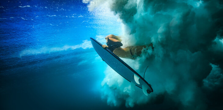 Surfer Duck Diving Under A Breaking Wave With Turbulent White Foam And Deep Blue Water