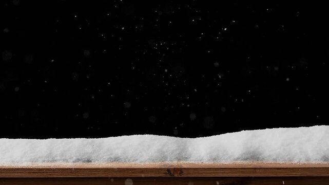 Snow falls on a wooden floor with a pile of snow