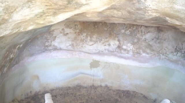 Ancient stone cistern inside underground limestone cave structure.