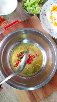 Adding fresh green onions and coriander into a spicy salad mixture with garlic, chili, and tomatoes. Cooking traditional Thai food dressing in a bowl