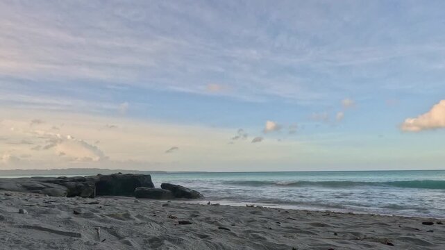 Timelapse of Kalapathar Beach with Gentle Waves, Black Rocks, and Soft Cloud Movement