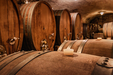 Obraz premium Wine barrels aging in a traditional underground cellar, showcasing the winemaking process and a rustic, authentic atmosphere