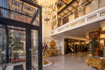 Naklejka premium Grand luxury hotel lobby in baroque style with massive crystal chandelier and golden reception desk