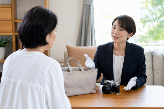 自宅でバッグとカメラを相談する女性客とスタッフ