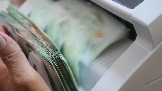 An automated cash counting machine money counter quickly counts multiple Thai's banknotes with precision. The device efficiently handles paper currency for banking and financial operations.
