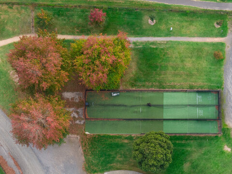 Aerial view of practice cricket pitches and trees in colourful Autumn foliage in green parkland