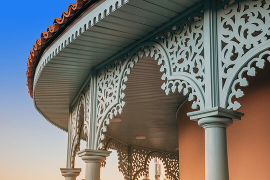 Elaborate architectural detail featuring intricate wood carving, decorative arches, and a balcony against a clear blue sky