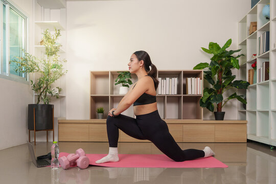 Asian woman doing lunge stretch on mat at home for fitness