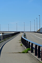 Naklejka premium Scenic vertical view of an empty pedestrian walkway and road ramp on a modern bridge under a clear blue sky, Fukushima Japan.