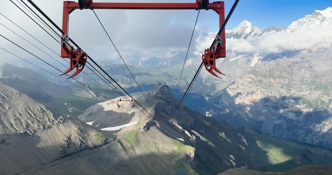 Scenic cable car perspective above high mountains with alpine valleys, snowy peaks and breathtaking nature views.