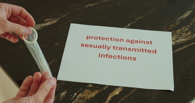 Hands holding a condom beside an STI protection message, representing safe sex, prevention and sexual health awareness.