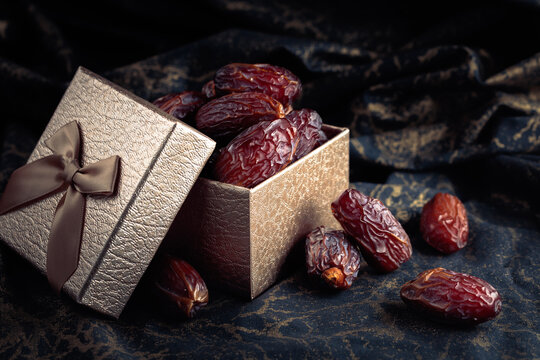 Dates in a gift box on black fabric with gold ornamentation.