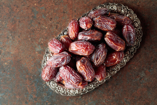 Dried dates fruit in silver tray on a rustic background.
