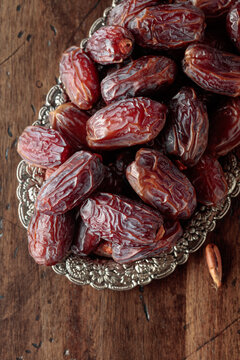 Dried dates fruit in silver tray on a wooden table.