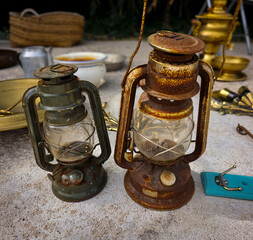 Rusty vintage kerosene lanterns with glass globes seen at an outdoor flea market during sunny day © catocala
