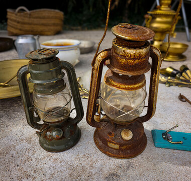 Rusty vintage kerosene lanterns with glass globes seen at an outdoor flea market during sunny day