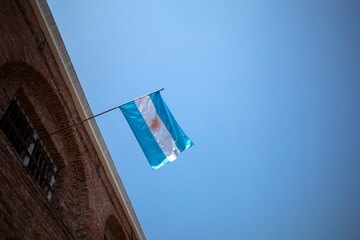 Obraz premium The National flag of Argentina on a historic old building with blue sky background