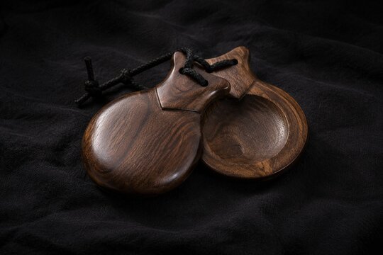 Traditional flamenco castanets resting on dark textured fabric.